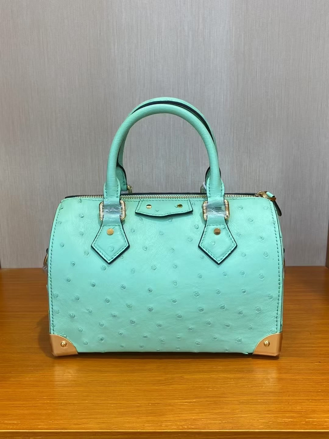Women's genuine ostrich skin leather top handle pillow handbag by Rossie Viren, showcasing textured black leather and elegant design.