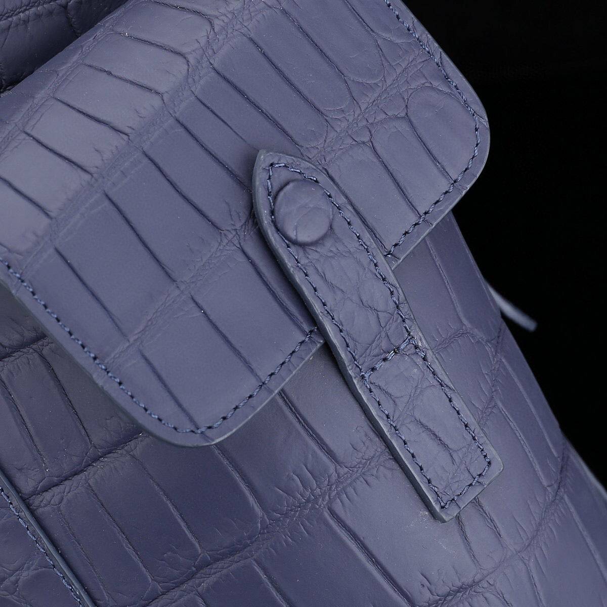 Dark blue crocodile leather backpack by Rossie Viren with a sleek design and sturdy straps, showcasing luxurious texture and craftsmanship.