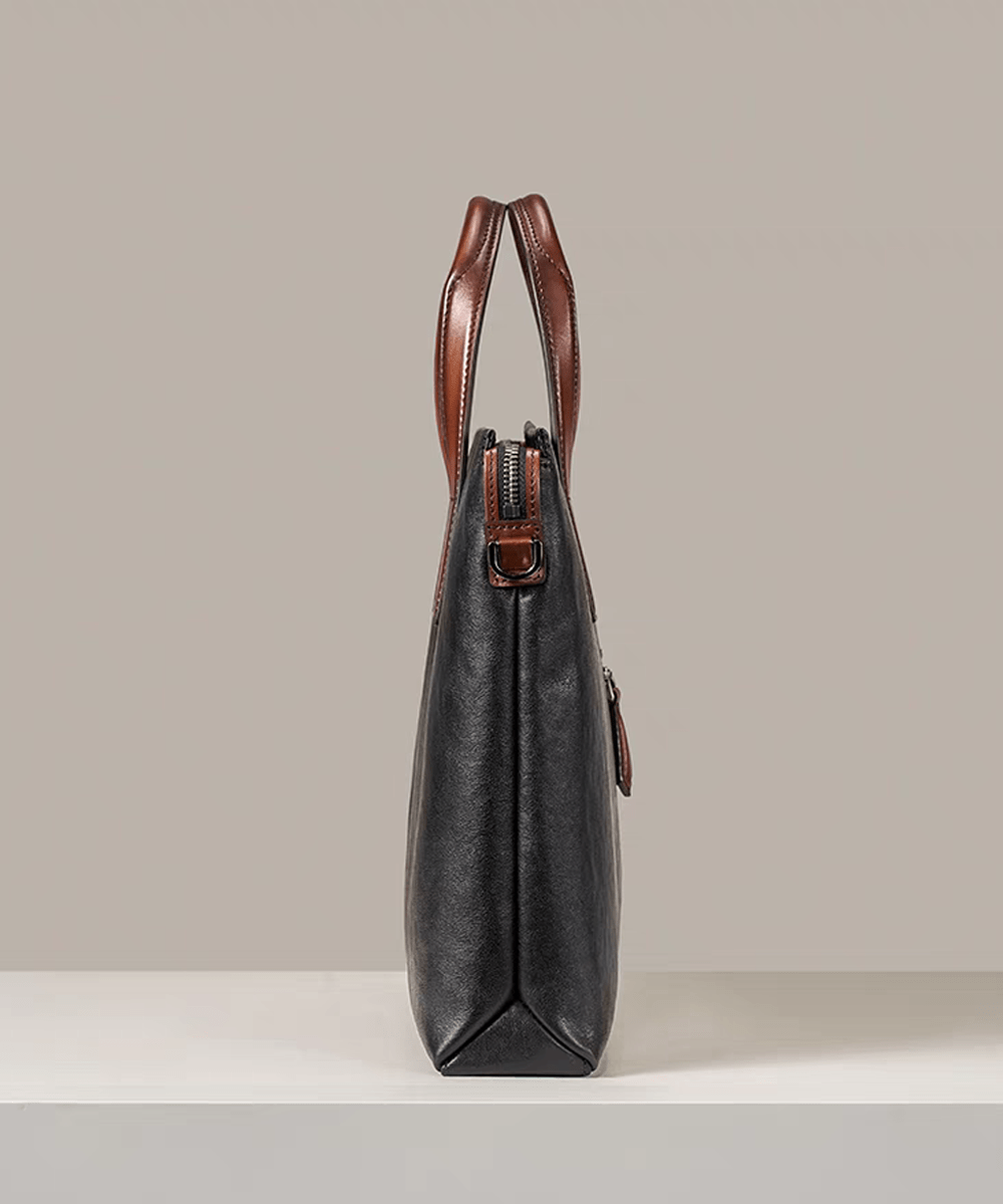 Black 15-inch Togo leather laptop briefcase bag by Rossie Viren, showcasing sleek design with sturdy handles and smooth leather surface.