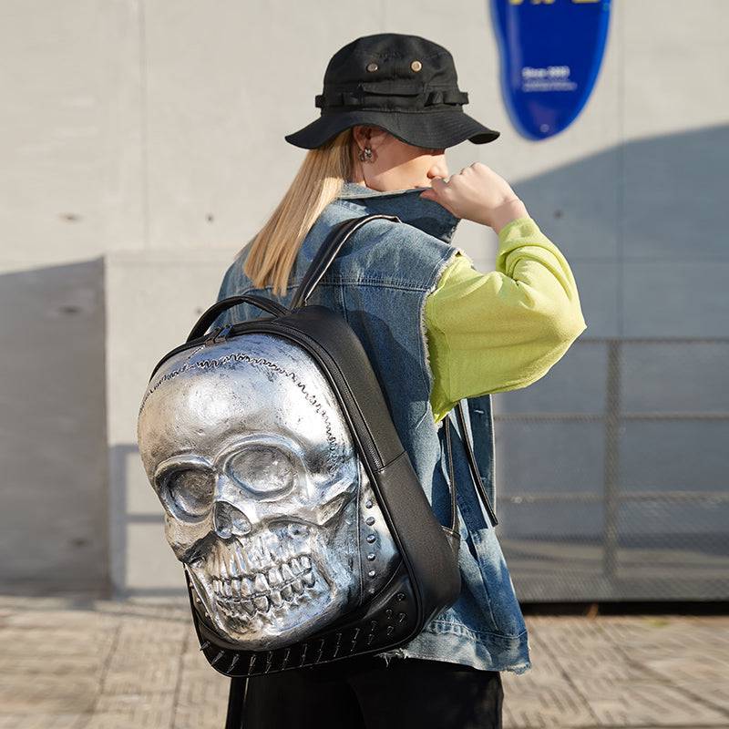 Unisex 3D skull backpack by Rossie Viren featuring a smiling skull design, studded accents, large capacity, ideal for laptops.