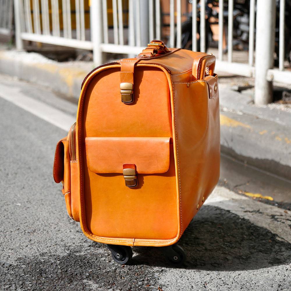 Vintage vegetable tanned leather carry-on rolling suitcase by Rossie Viren, with universal spinner wheels in camel color.