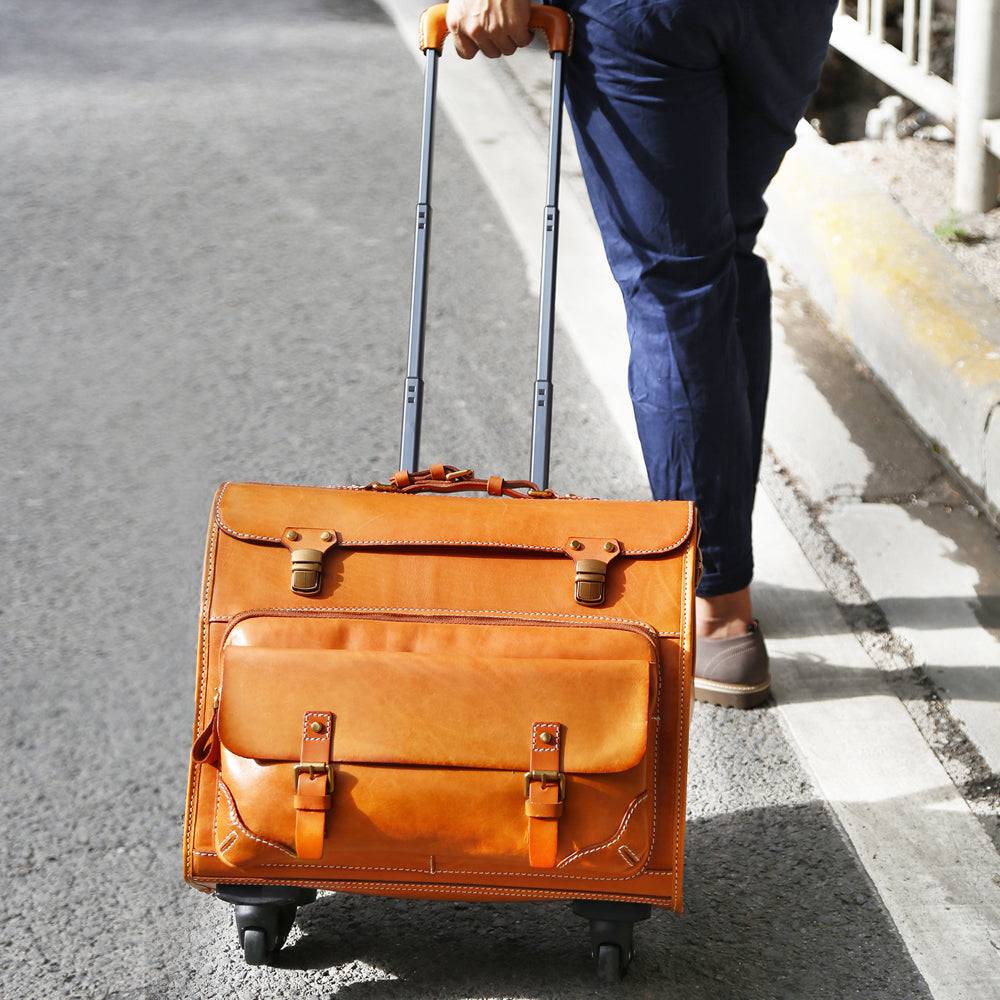 Vintage camel leather carry-on rolling suitcase by Rossie Viren with universal spinner wheels and classic vegetable tanned finish.