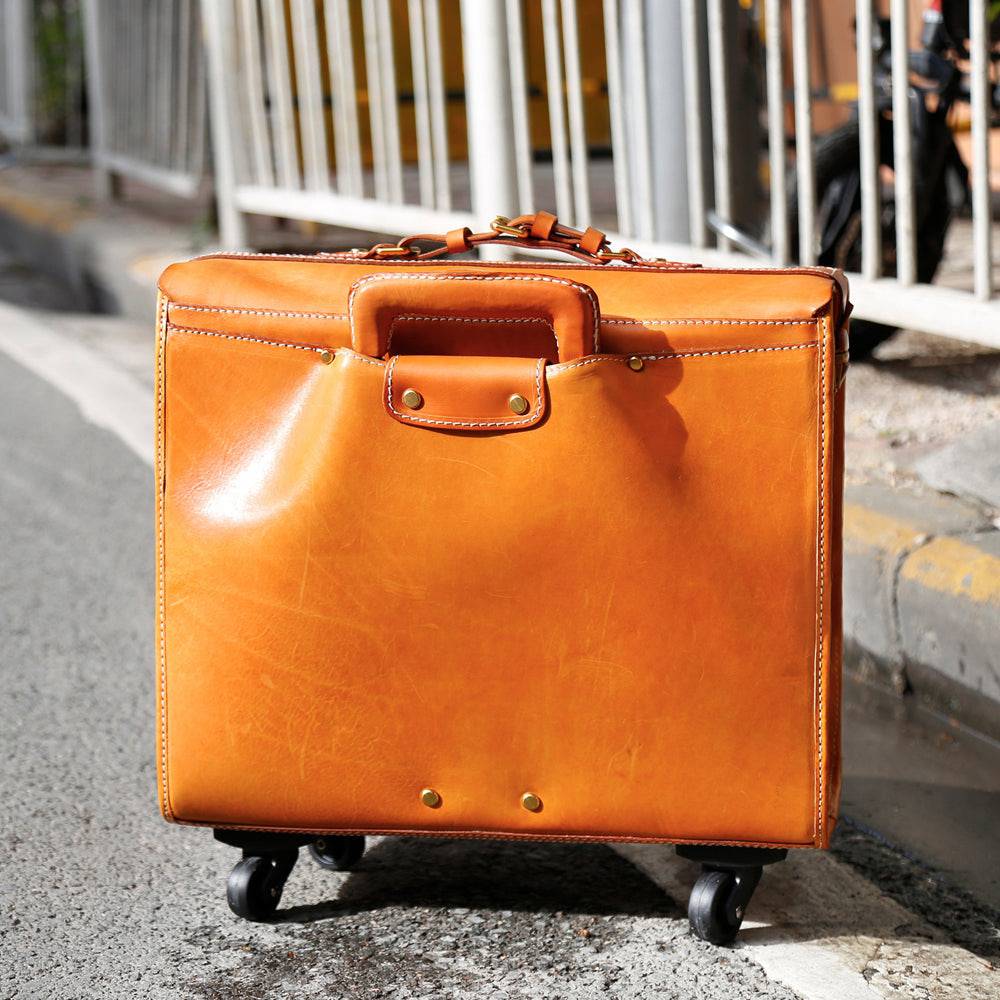 Vintage 20-inch vegetable tanned leather carry-on rolling suitcase by Rossie Viren with spinner wheels in camel color.