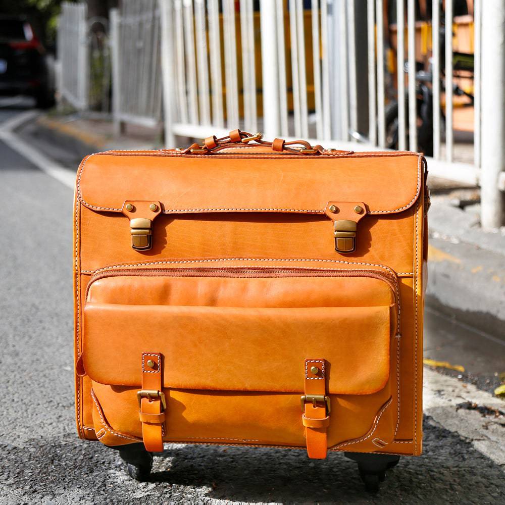 Vintage vegetable-tanned leather carry-on rolling luggage by Rossie Viren, camel-colored suitcase with spinner wheels and classic design.