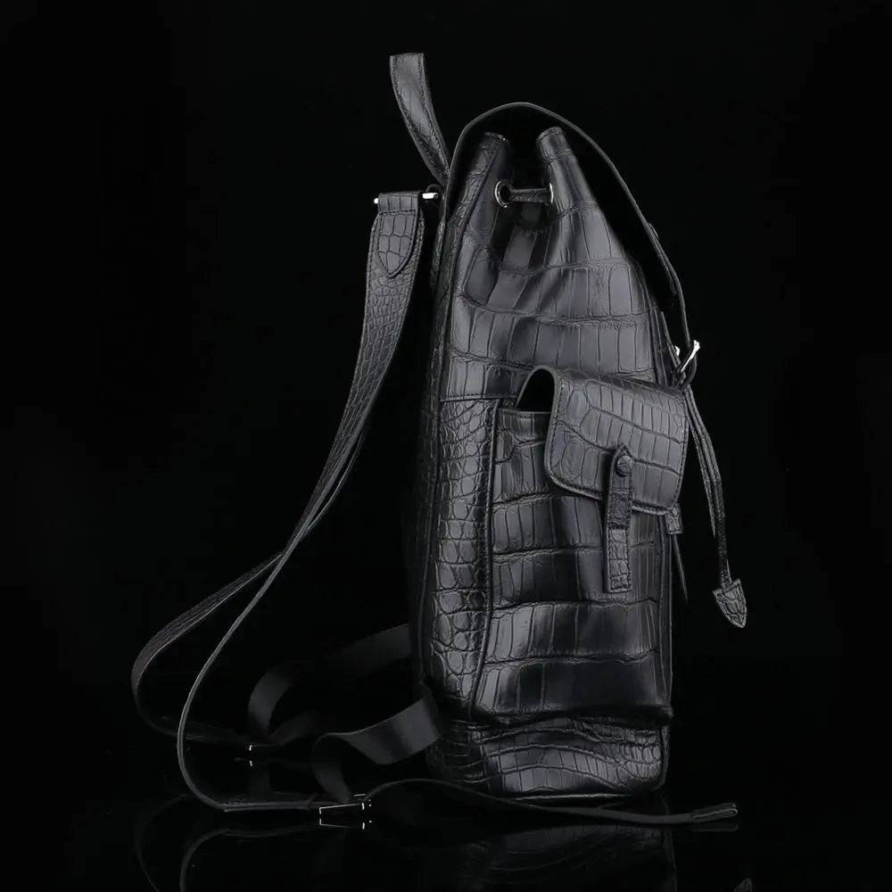 Black crocodile leather backpack by Rossie Viren with sleek design and textured crocodile pattern, featuring adjustable straps and top handle.