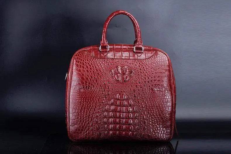 Red crocodile leather duffel travel bag by Rossie Viren, showcasing its textured surface and sturdy handles.