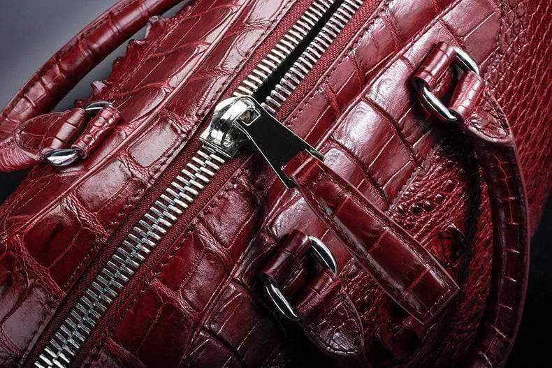 Red crocodile leather duffel travel bag by Rossie Viren with sturdy handles and sleek design.