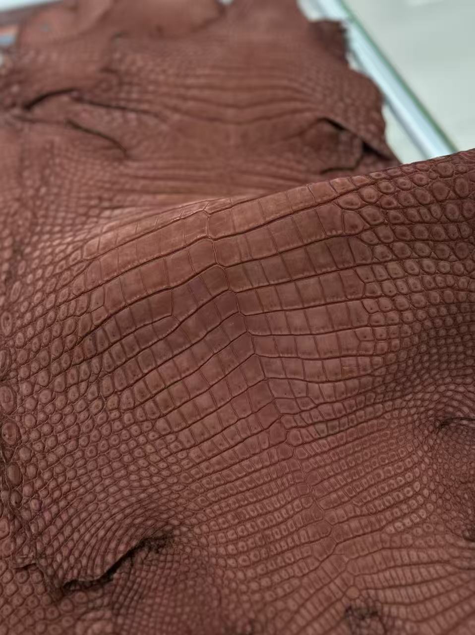 Beige unisex clutch bag with crocodile leather texture, zipper handle and Rossie Viren branding on the genuine nubuck leather.