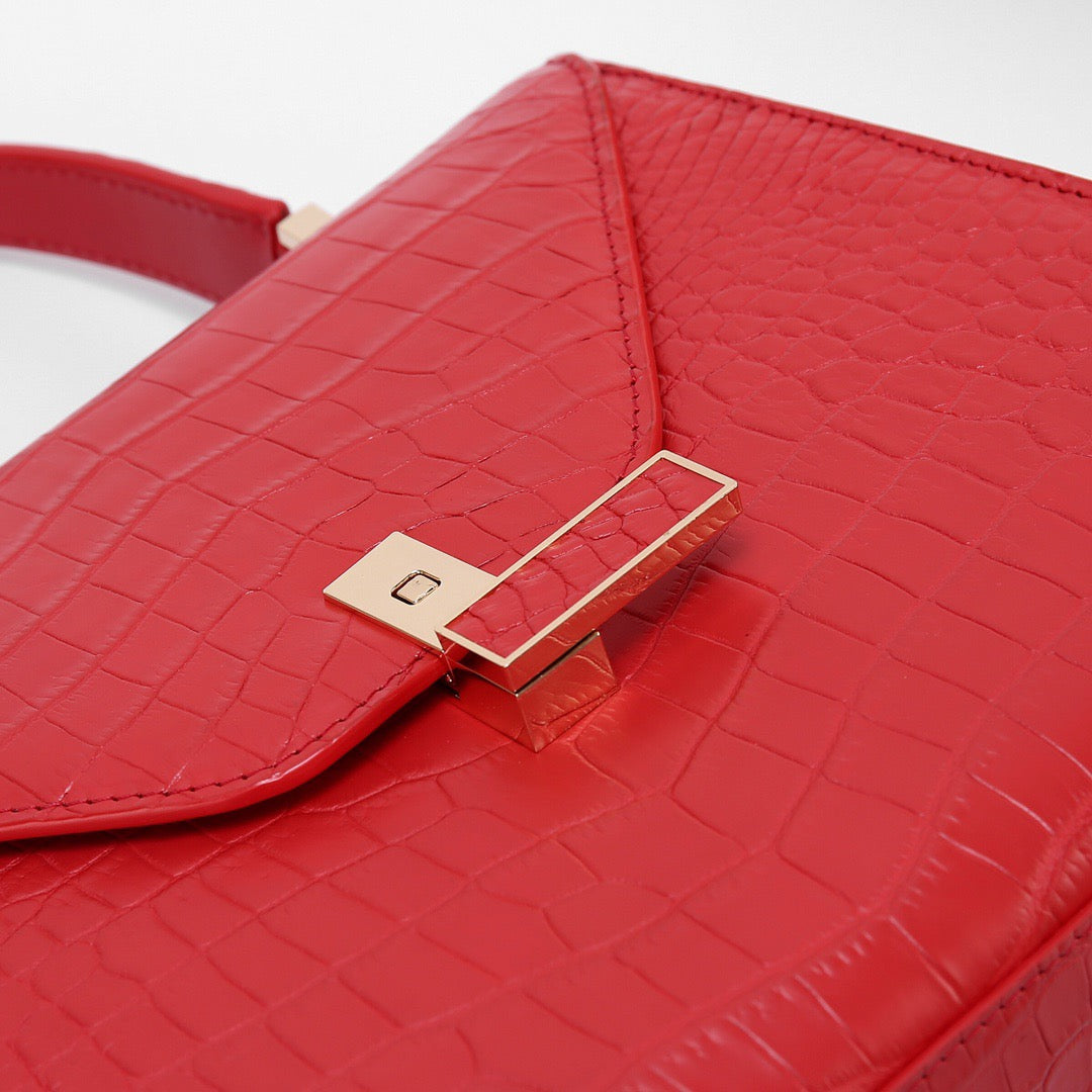 Red crocodile skin leather top handle bag by Rossie Viren, showcasing a luxurious textured finish and elegant design.