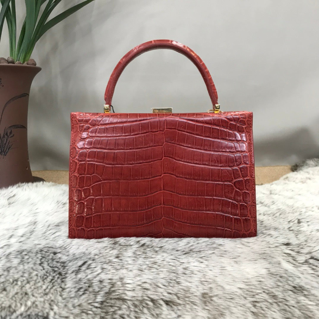 Crocodile leather evening clutch bag with top handle by Rossie Viren, featuring a sleek and elegant design for formal occasions.