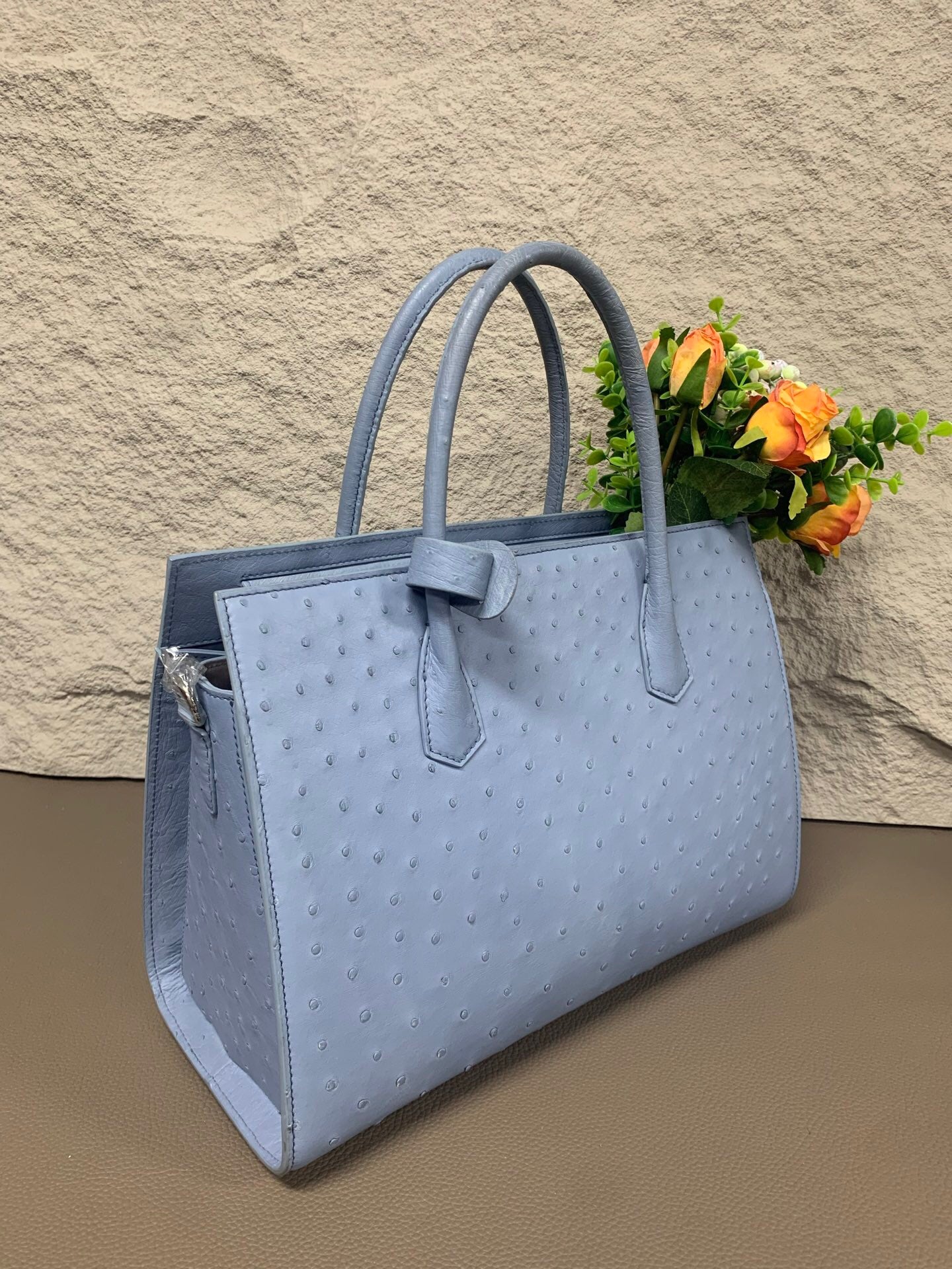 Women's ostrich skin leather handbag with top handle by Rossie Viren, showcasing its textured leather and elegant design.