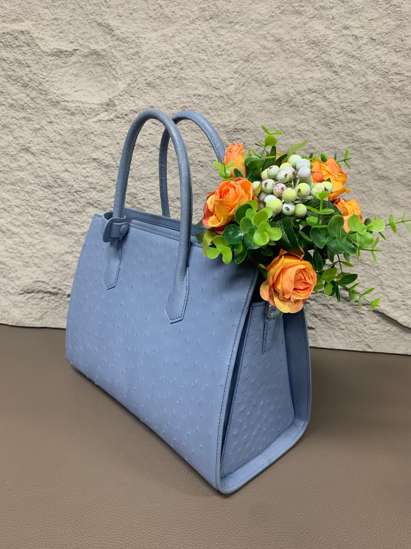 Women's ostrich skin leather handbag with top handle by Rossie Viren, showing textured black leather and elegant design.