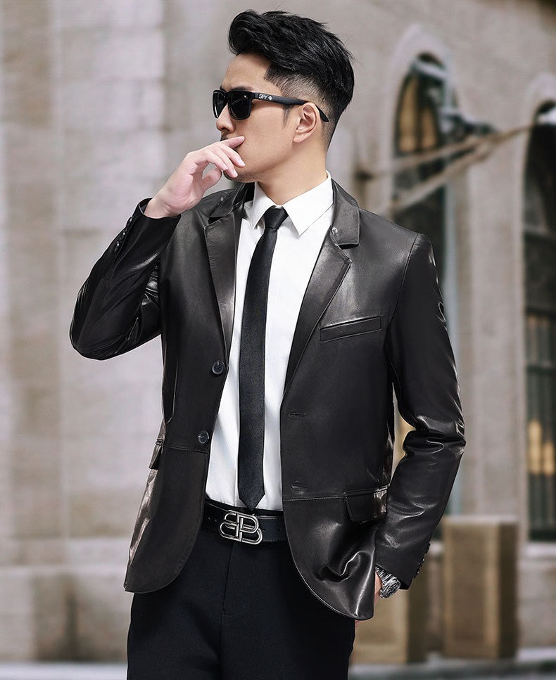 Black leather blazer jacket by Rossie Viren, tailored fit with lapels and button closure, displayed on a hanger on a white background.