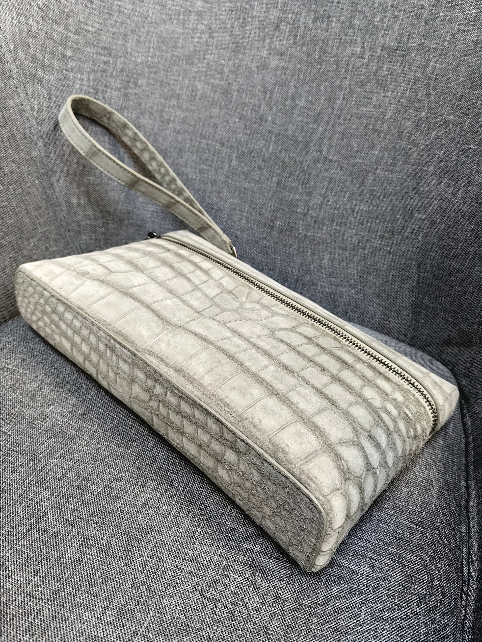 Unisex Rossie Viren crocodile skin leather clutch bag with zipper handle and nubuck finish.