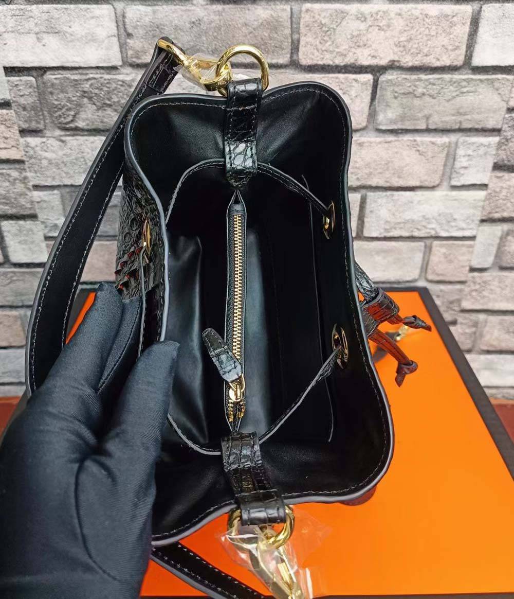 Crocodile leather bucket handbag by Rossie Viren with a drawstring closure and gold-tone hardware, showcasing textured crocodile skin.