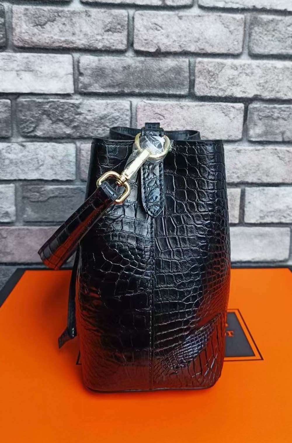 Rossie Viren crocodile leather bucket handbag with gold-tone hardware and adjustable strap, featuring a spacious interior.