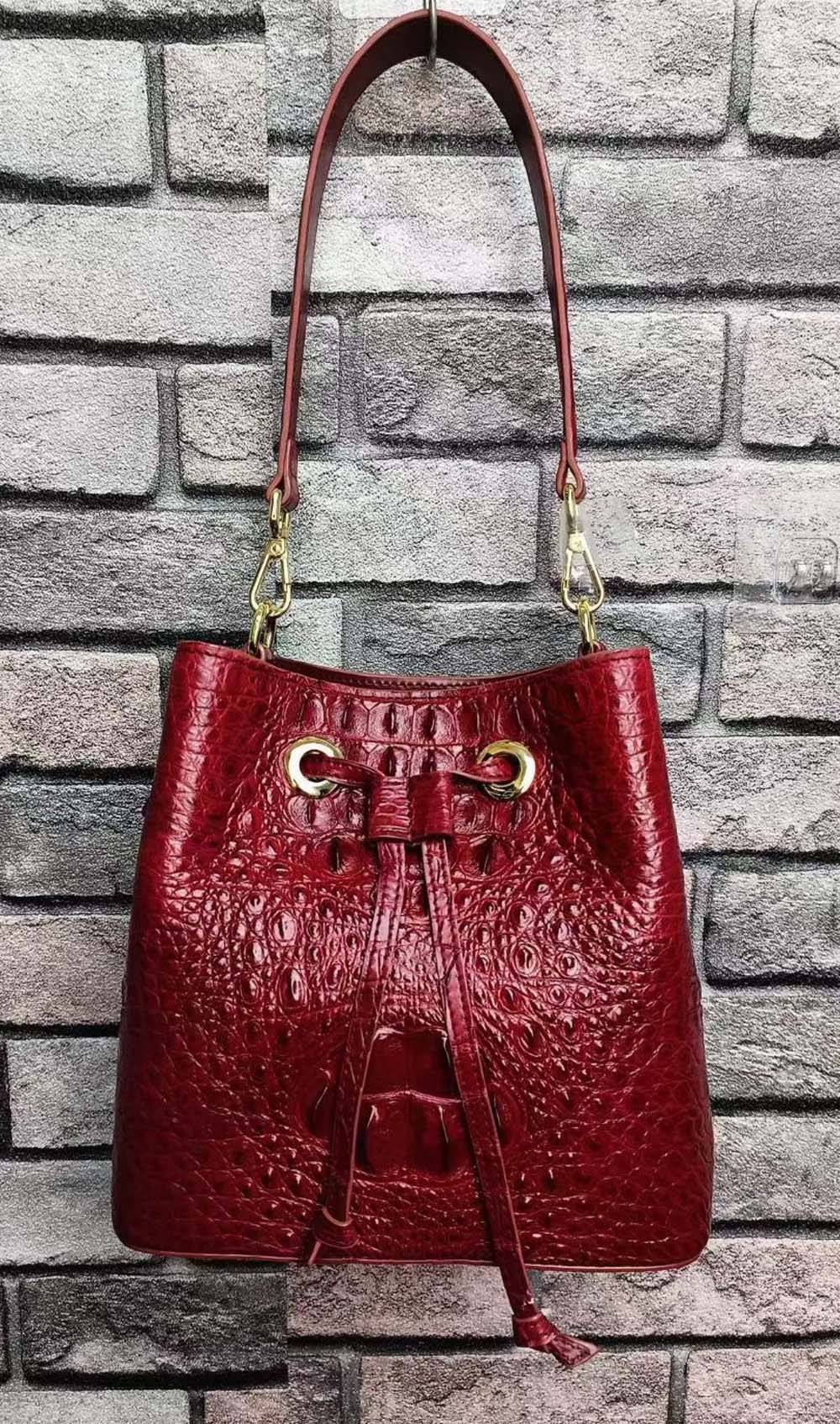 Rossie Viren crocodile leather bucket handbag with a drawstring closure and gold-tone hardware, featuring a structured silhouette.