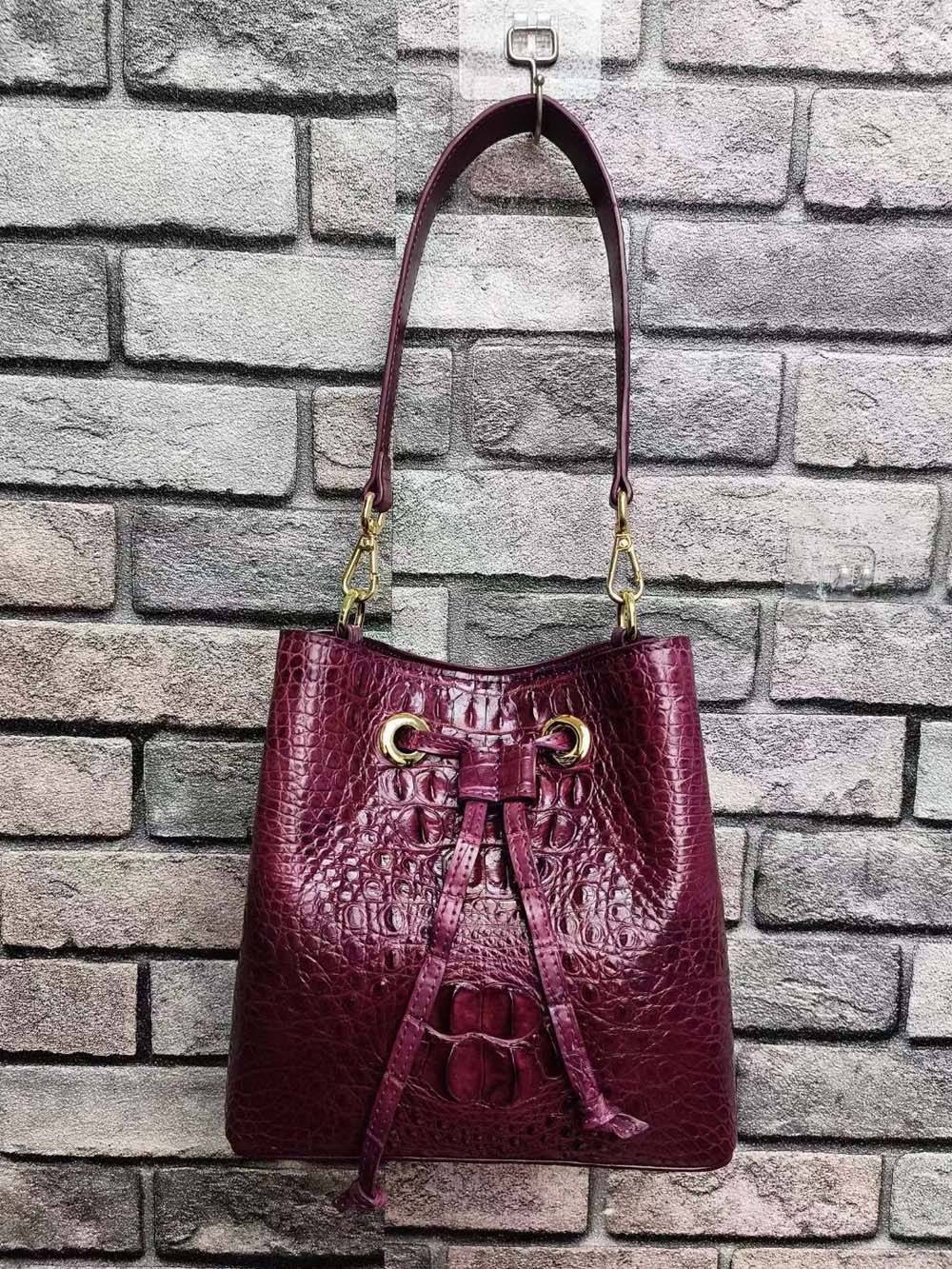 Rossie Viren crocodile leather bucket handbag with gold-tone hardware and adjustable strap, showcasing textured surface and stylish design.