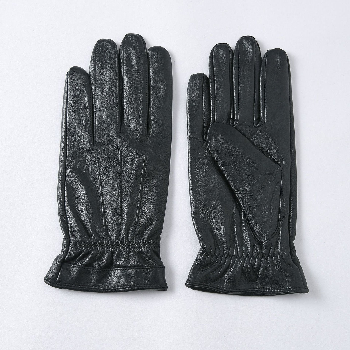 Black leather men's gloves by Rossie Viren, stylish and basic, displayed on a handbag for a sophisticated look.