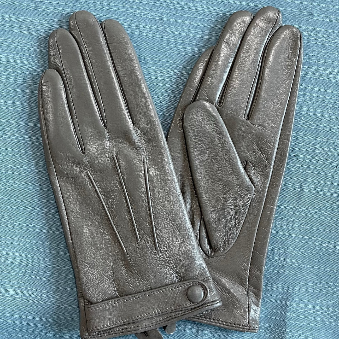 Women's soft goatskin leather fashion snap cuff gloves, stylish and cozy accessory, shown with a handbag in the image.