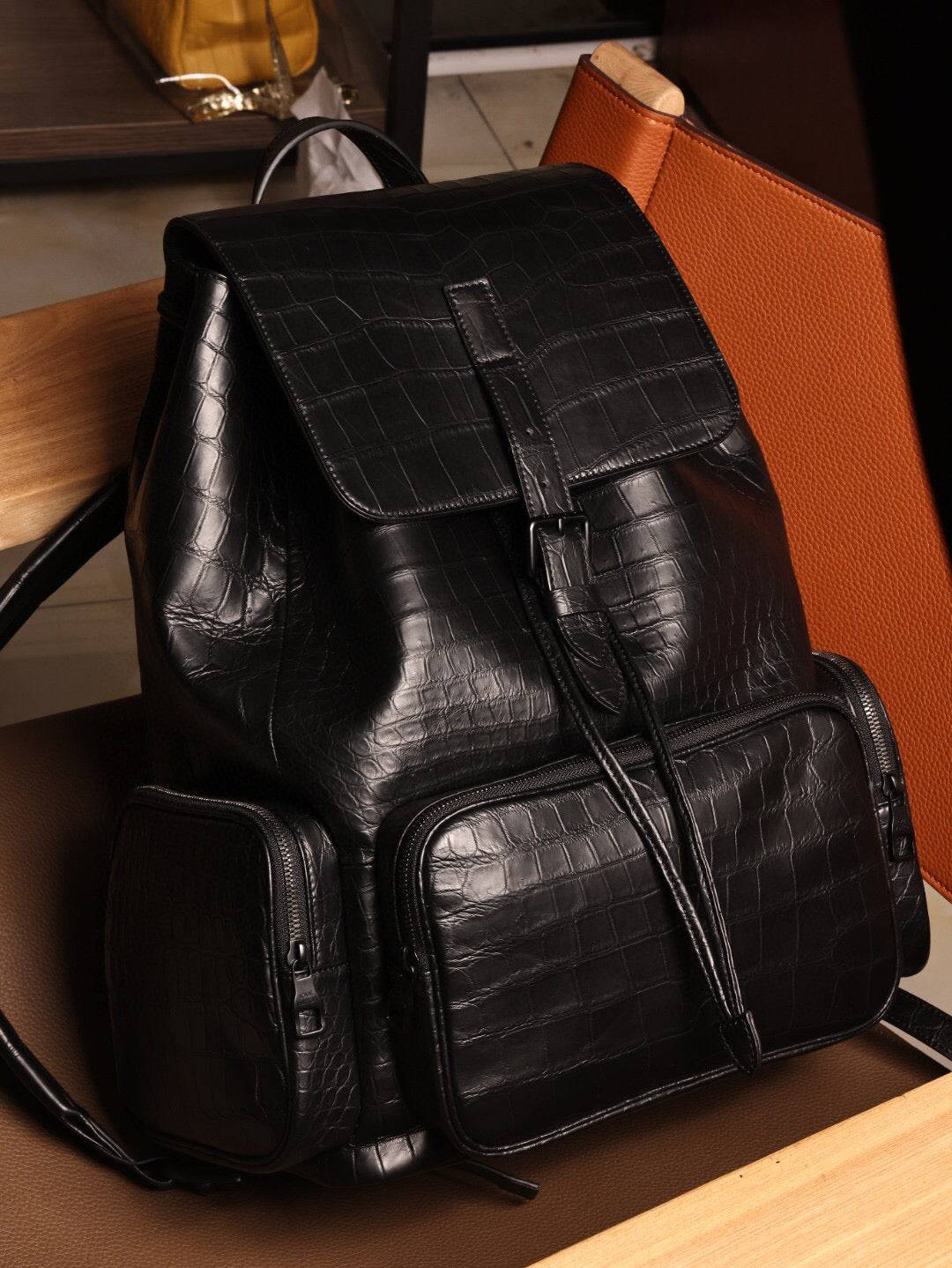 Unisex black crocodile leather handbag by Rossie Viren with adjustable straps and sleek design, shown from the front view.