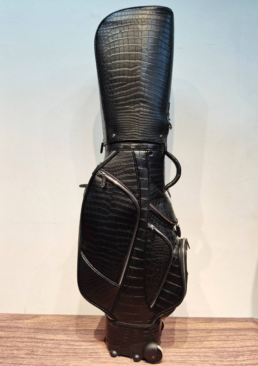 Black crocodile belly leather golf bag by Rossie Viren, versatile golf set with cart and stand options, featuring a roller for easy transport.