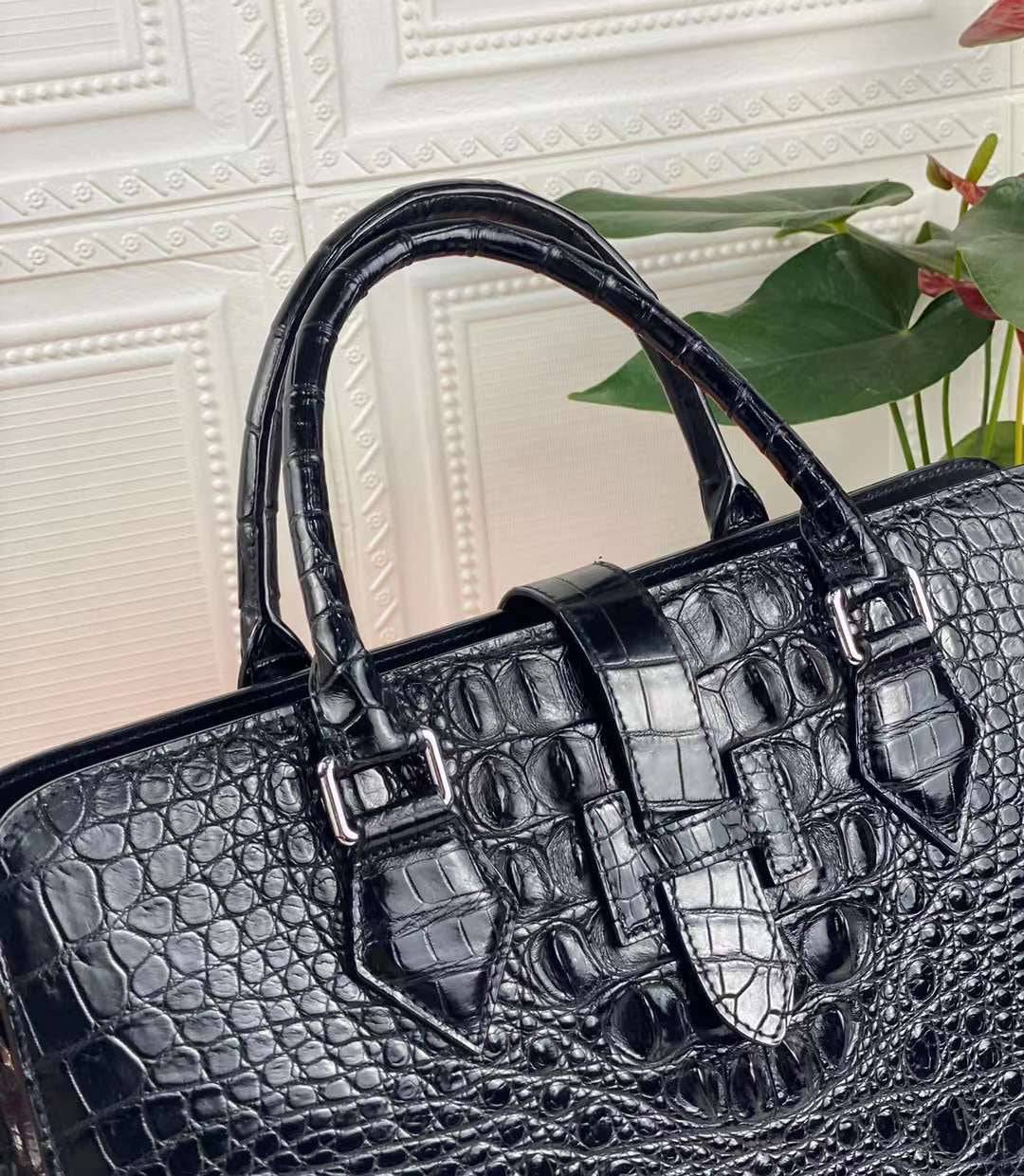 Black Rossie Viren crocodile leather briefcase with a sleek, textured crocodile skin surface and sturdy handle for professional use.