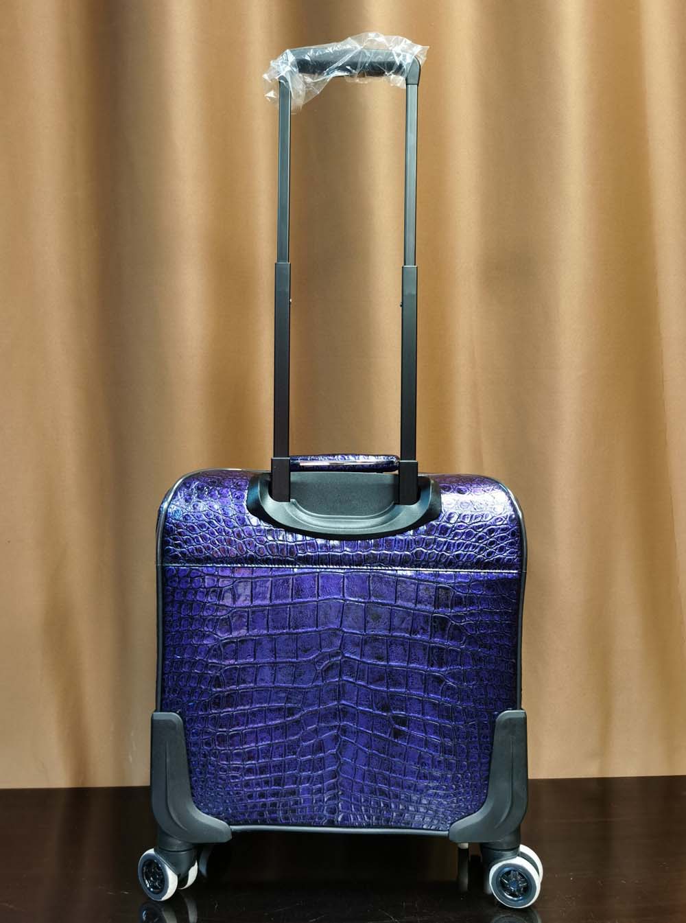 Purple crocodile leather 15-inch mini carry-on suitcase by Rossie Viren with a sleek design and sturdy handle.