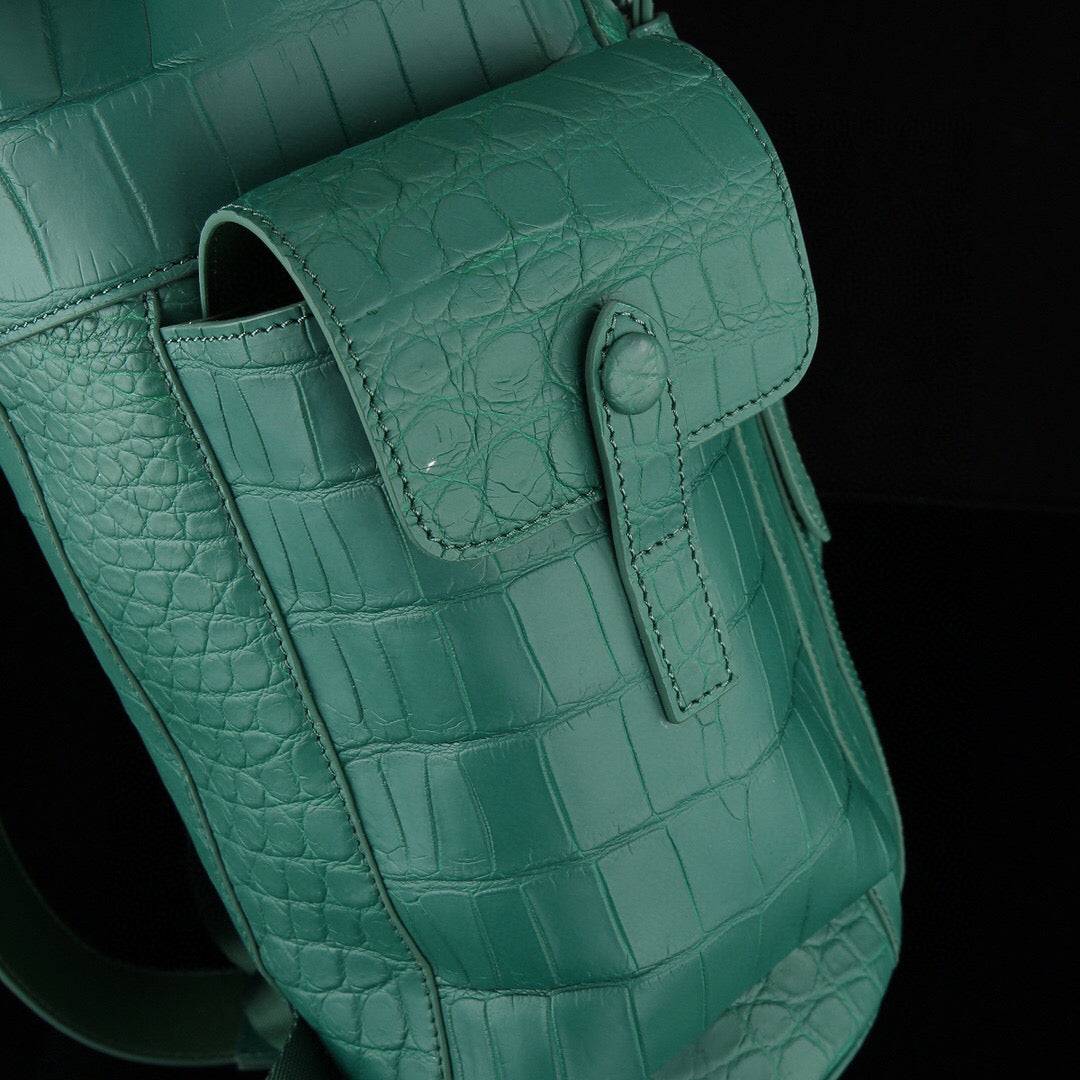 Dark green crocodile leather backpack by Rossie Viren with sturdy straps and textured crocodile pattern.
