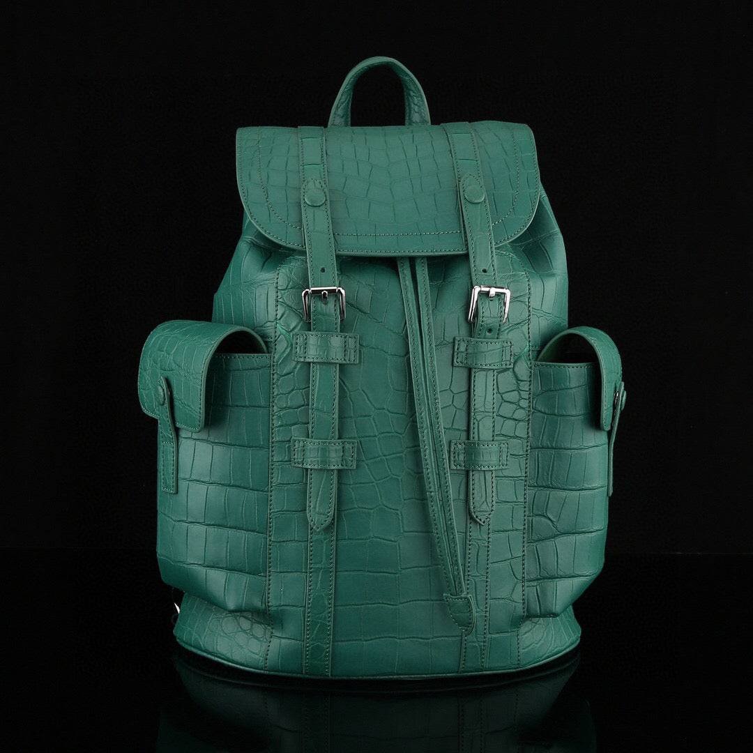 Dark green crocodile leather backpack by Rossie Viren with adjustable straps and silver hardware, showcasing the textured crocodile pattern.