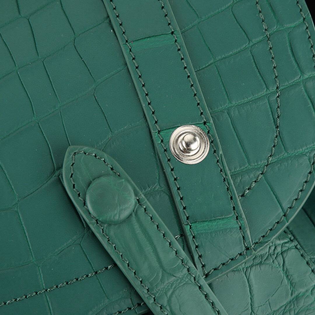 Dark green crocodile leather backpack by Rossie Viren with adjustable straps and a front pocket, showcasing luxurious textured leather.