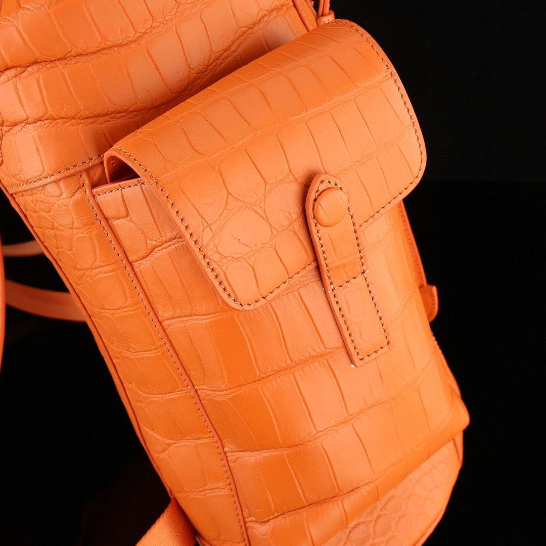 Orange crocodile leather backpack by Rossie Viren showing textured crocodile pattern, sturdy straps, and sleek design.