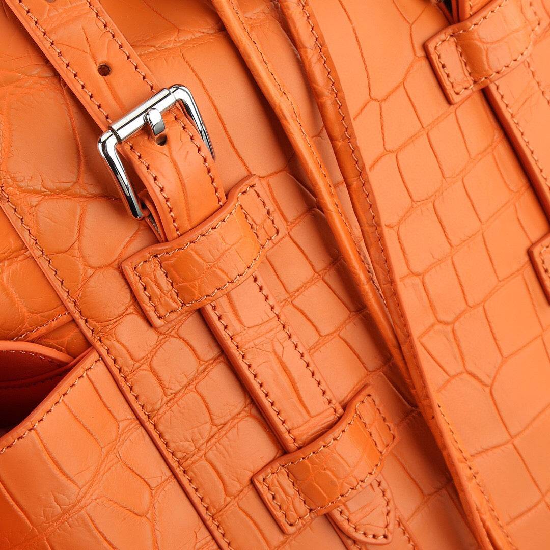 Orange crocodile leather backpack by Rossie Viren with a sleek design and sturdy straps, showcasing textured crocodile pattern.