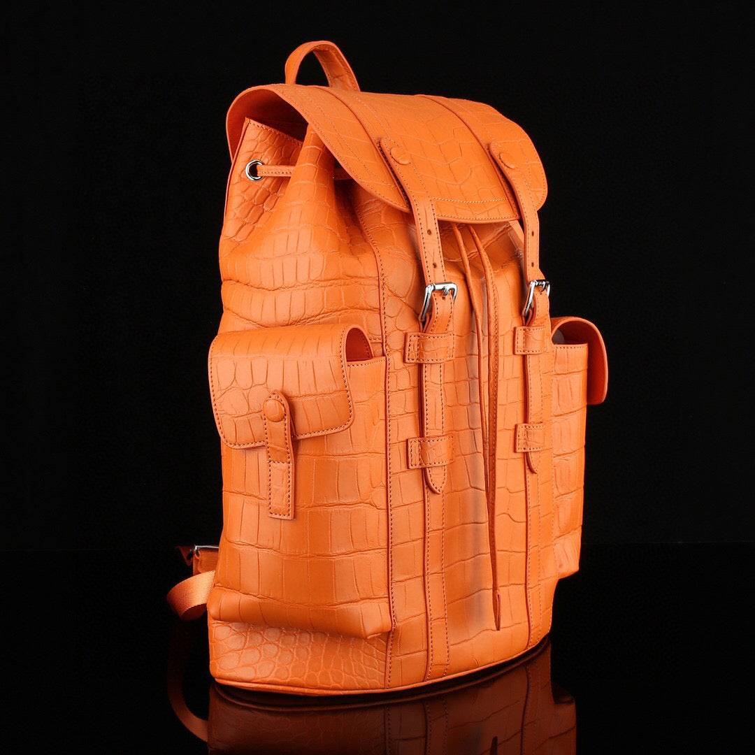 Orange crocodile leather backpack by Rossie Viren with sturdy straps and textured crocodile pattern on the front.