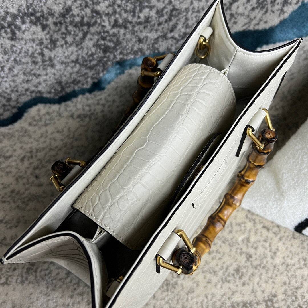 White crocodile skin leather shoulder crossbody bag with bamboo handle by Rossie Viren. Stylish handbag with textured crocodile pattern.