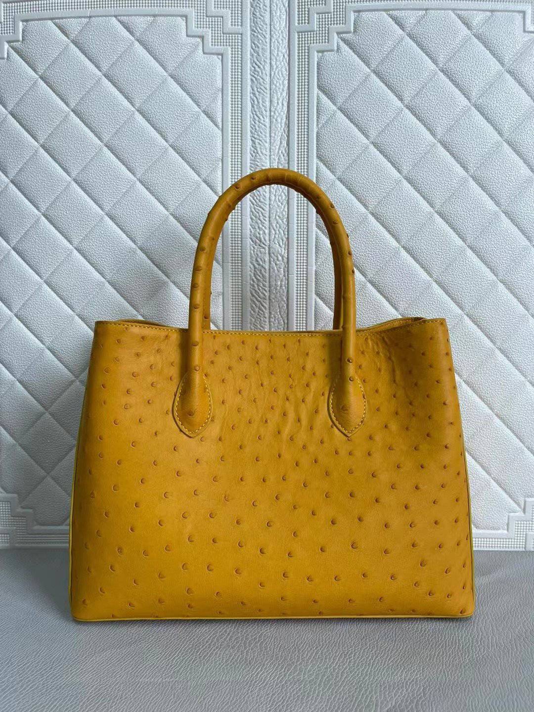 Rossie Viren women's ostrich leather handbag with top handle and cross-body strap in coral blue and yellow, 33cm wide.